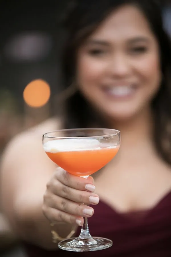 Woman cheers with a glass of mixed drink cocktail